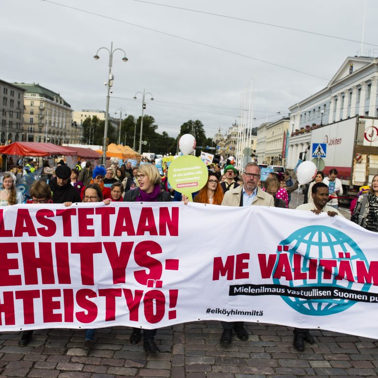 Mielenosoittajia Pelastetaan kehitysyhteistyö -bannerin takana Helsingin keskustassa.