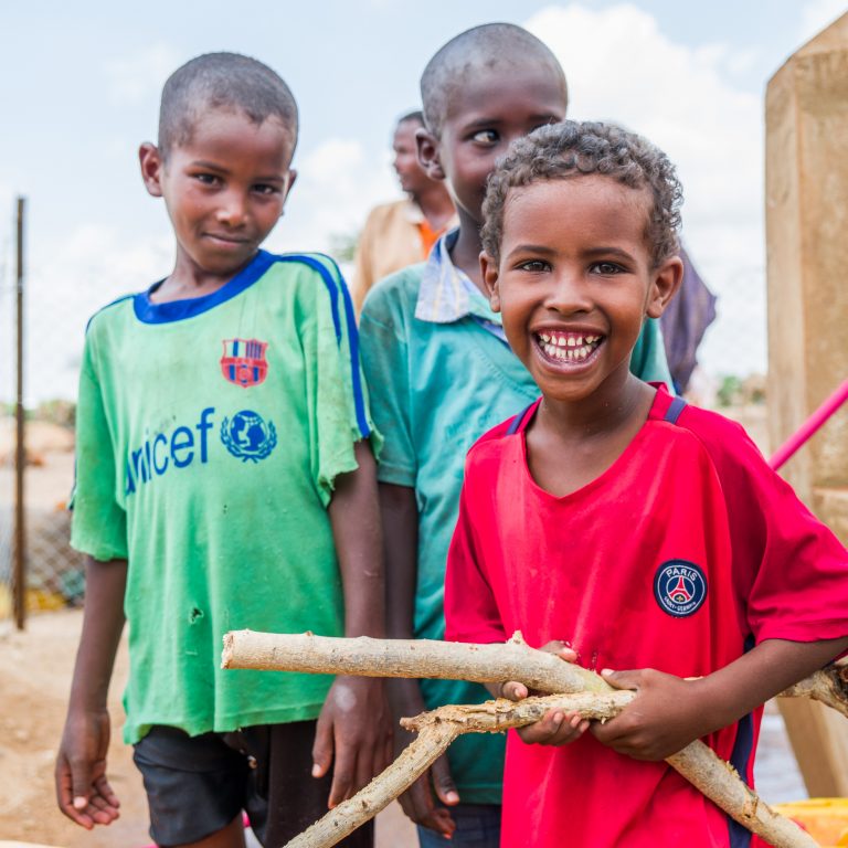 kolme iloista somalipoikaa kaivon luona