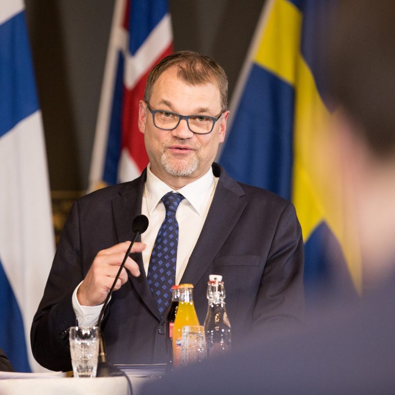 Kuvassa Kimmo Tiilikainen ja Juha Sipilä seisovat mikrofonin edessä.