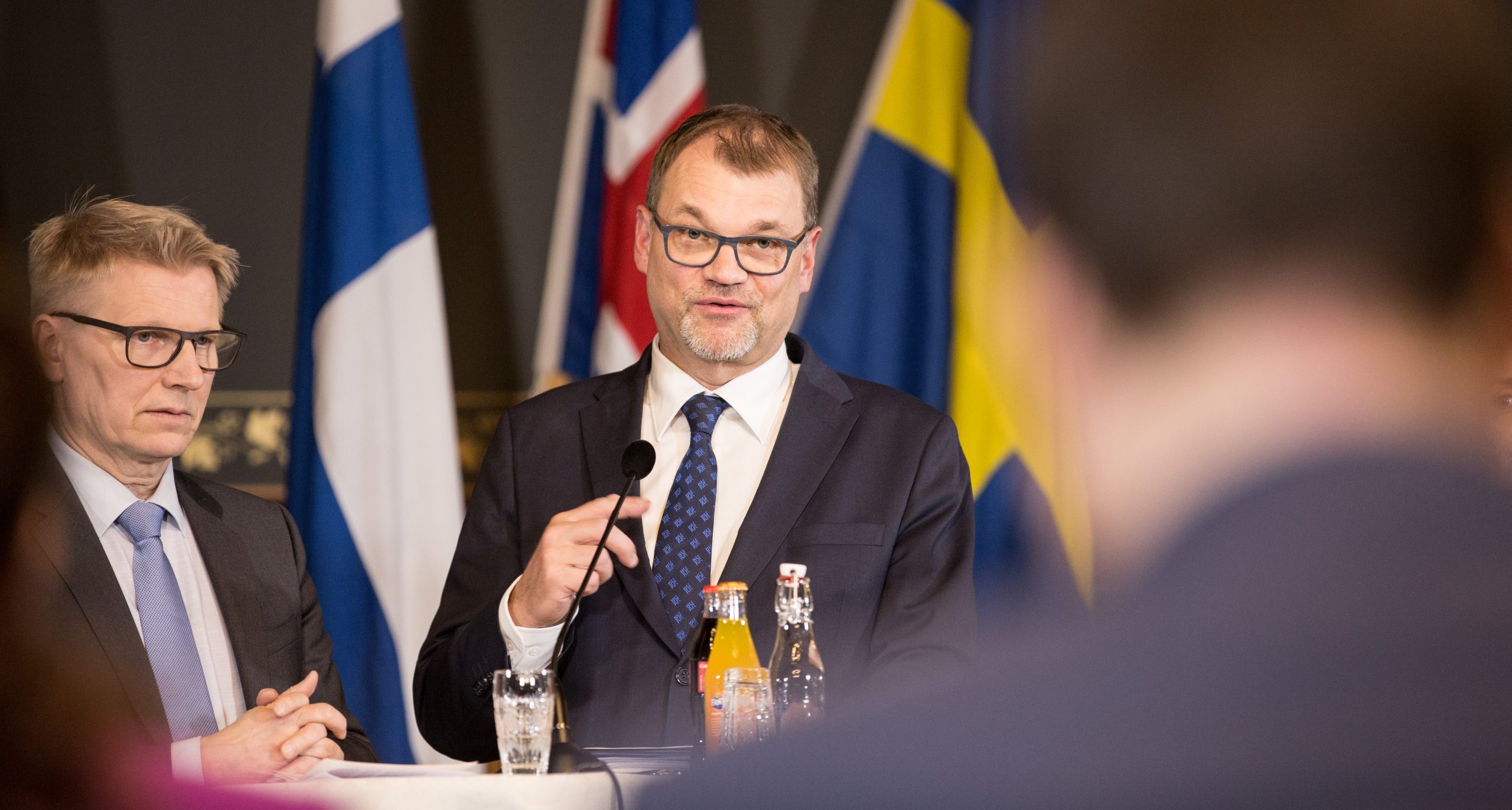 Kuvassa Kimmo Tiilikainen ja Juha Sipilä seisovat mikrofonin edessä.